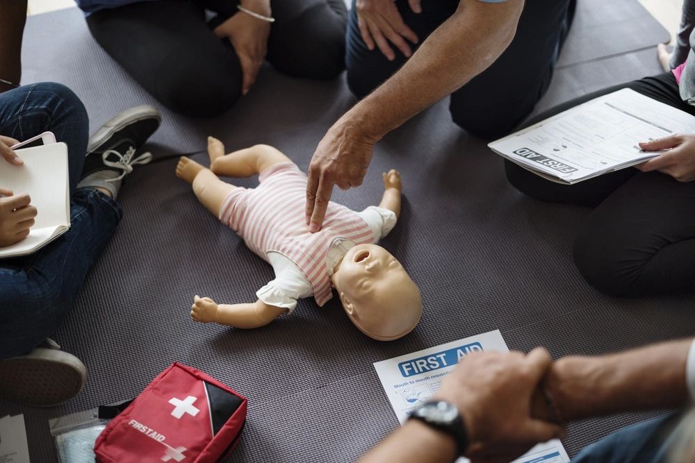 A person performing CPR on an infant manikin during a CPR class.