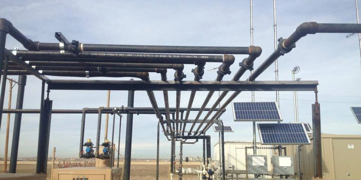 Industrial pipes and solar panels under a clear sky.