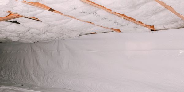 A crawl space with insulation and plastic vapor barrier installed.