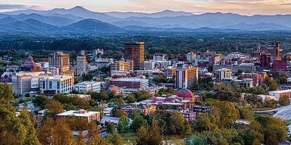 City skyline with mountains in the background during sunset.