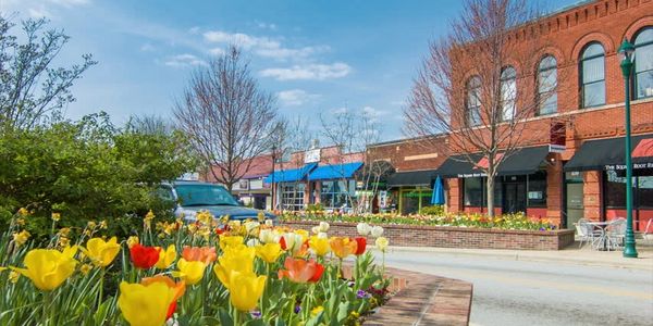 Colorful tulips bloom along a charming downtown street with brick buildings.