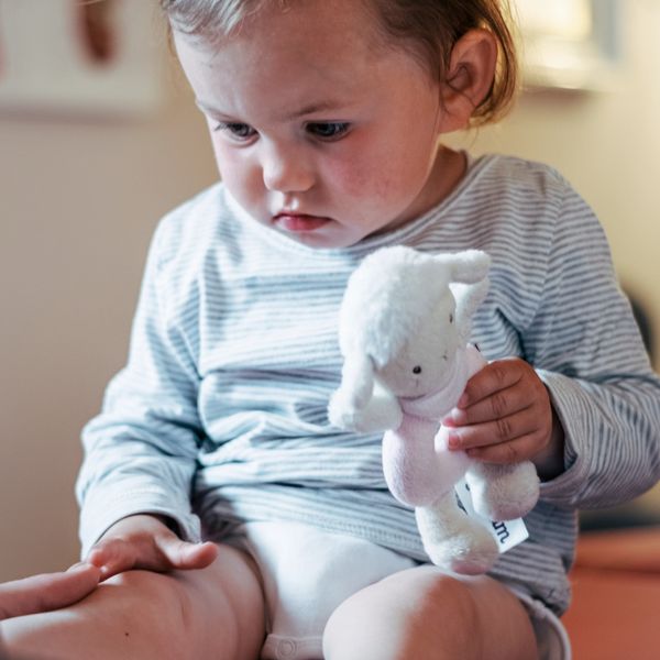 Osteopathin Ramona Prinz behandelt ein Kind an dessen Fuß, während es ein Kuscheltier hält.