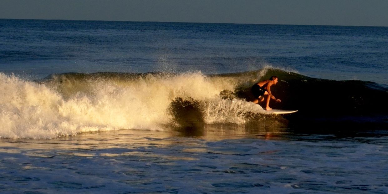 Surfer riding a wave at sunset.