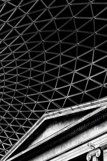 Black and white photo of a modern geometric roof over classical architecture.