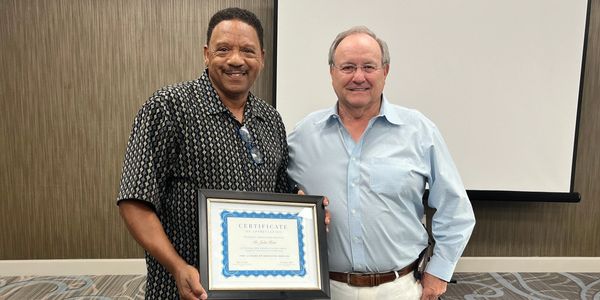 Two men posing with a certificate indoors.