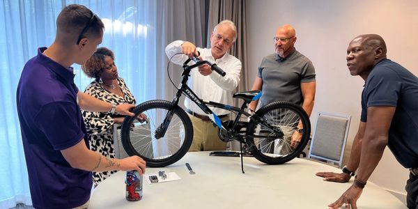 Group assembling a bicycle around a table indoors.