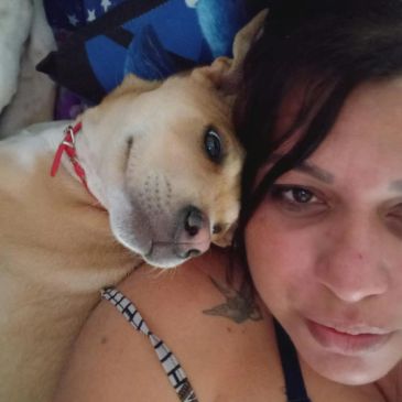 Woman lying next to a dog, both looking relaxed.