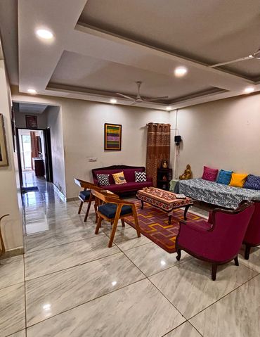 A cozy living room with colorful cushions and wooden chairs.