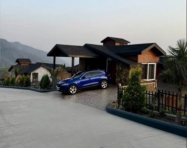 Modern house with a blue car parked in the driveway during dusk.
