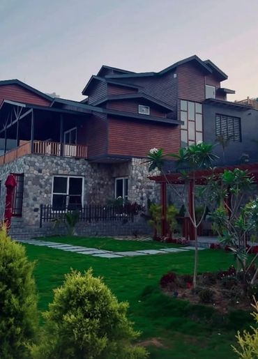 A modern house with stone and wood exterior surrounded by a lush garden.
