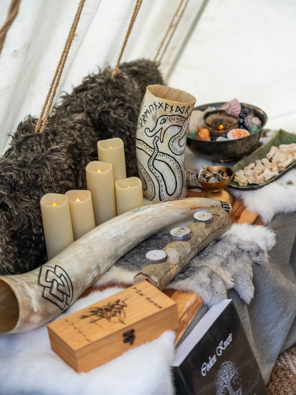 Viking-inspired setting with candles, carved drinking horn, and runic symbols.