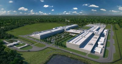 Aerial view of a large industrial complex surrounded by greenery under a blue sky.