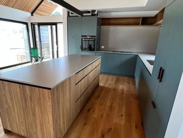 Modern kitchen with wooden island and teal cabinets.