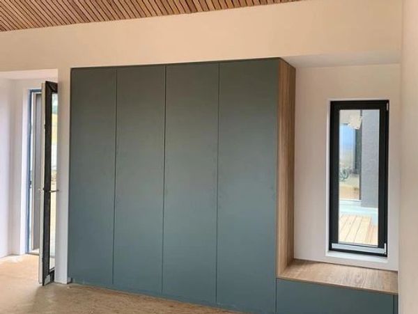 Modern built-in wardrobe with a bench and window.