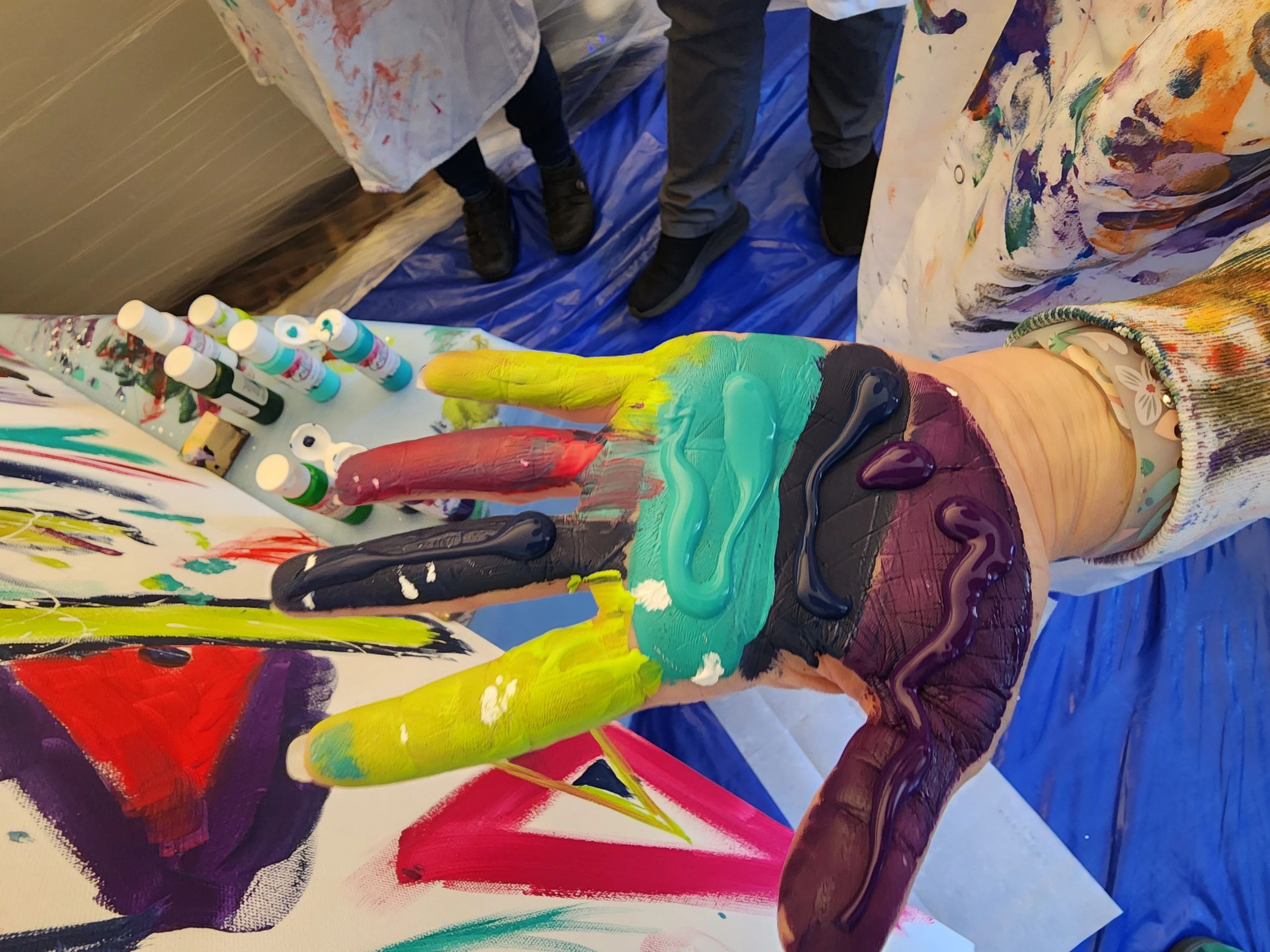 Hand covered in colorful paint at an art activity.