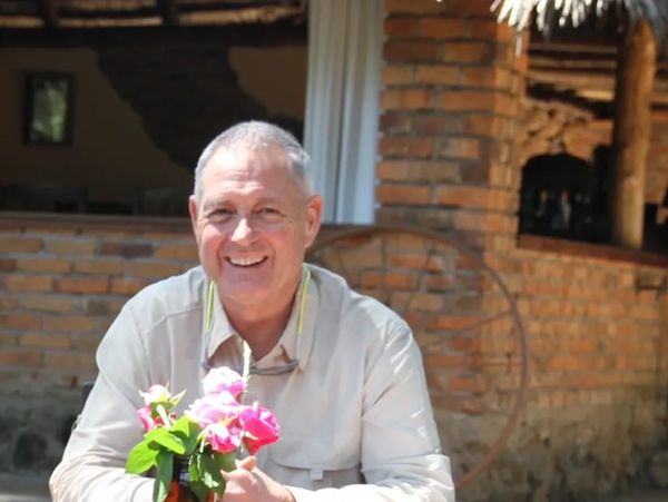 Phil Smart at Coffee Lodge - Arusha, Tanzania in front of flowers in the sunshine