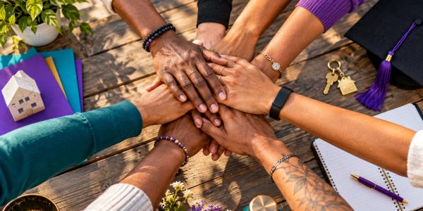 Diverse group putting their hands together in unity.