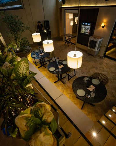 Restaurante à noite com luzes pendentes e mesas arrumadas.