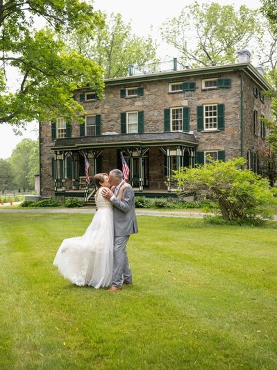 bride and groom in front of stone house at the sugarhouse