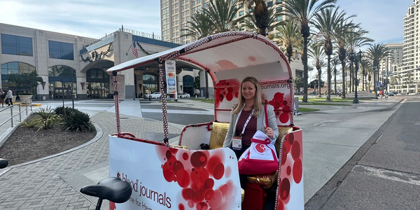 Woman sitting in a decorated pedicab in an urban area with palm trees.