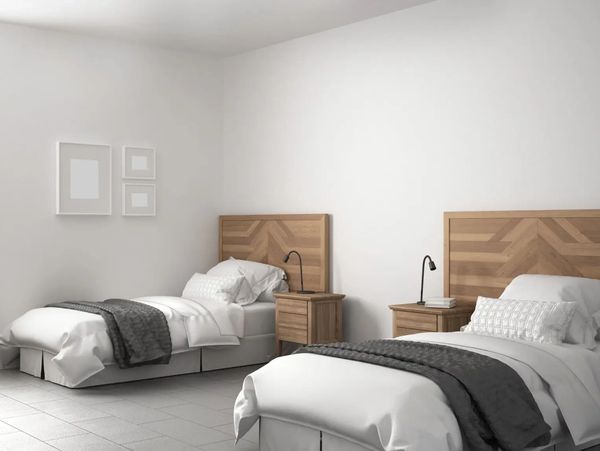 Minimalist bedroom with two twin beds and wooden headboards.