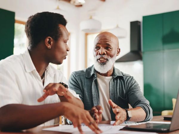 Two men engaged in a deep conversation at a kitchen table.