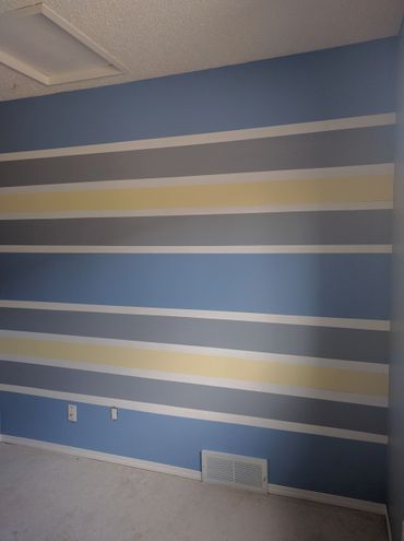 A wall painted with horizontal stripes in blue, gray, yellow, and white.