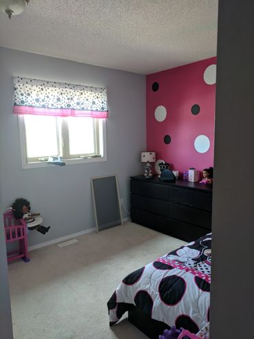 Child's bedroom with pink and black polka dot theme and toys.