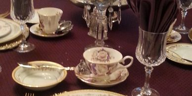 dining table with white plates with purple flowers and crystal glasses and tea cups