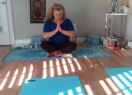woman praying seated on yoga mat legs criss cross
