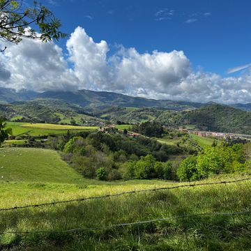 View of rolling hills and mountains in the background. Big white puffy clouds in the sky. Camino de 