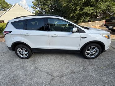 White SUV parked on driveway by a house.