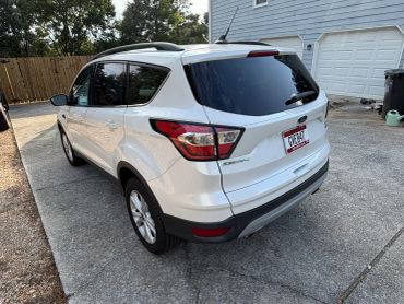 White Ford Escape parked in a driveway.