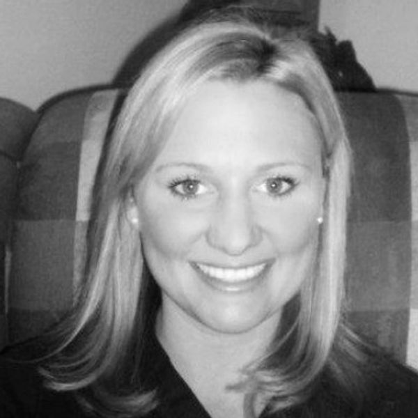 Smiling blonde woman with blue eyes sitting indoors.