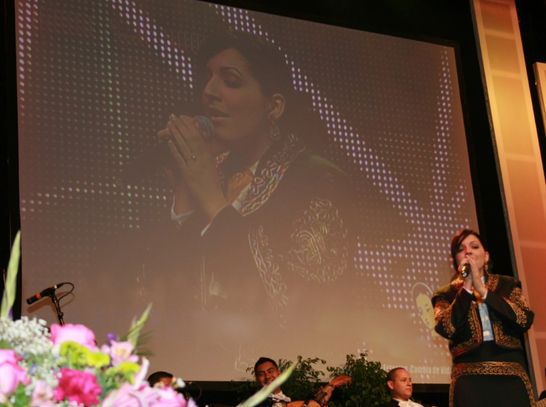 A women in black dress singing on the mic