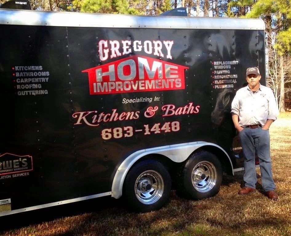 Man stands beside Gregory Home Improvements trailer.
