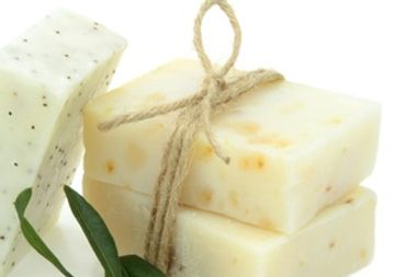Three natural soap bars with a sprig of green leaves on white background.