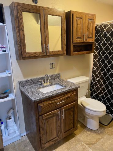 Bathroom with wooden cabinets, granite countertop, and white toilet.