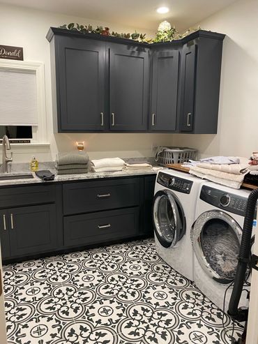 Modern laundry room with dark cabinets and patterned floor tiles.
