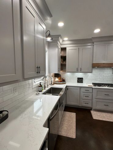 Modern kitchen with white cabinets and marble countertops.