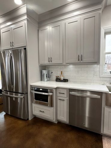 Modern kitchen corner with stainless steel appliances and white cabinets.
