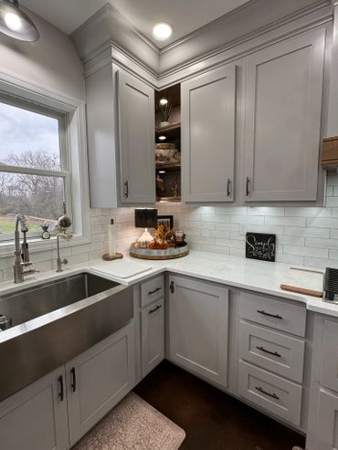 Modern kitchen corner with stainless steel sink and white cabinets.