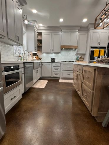Modern kitchen with white cabinets and brown floors.