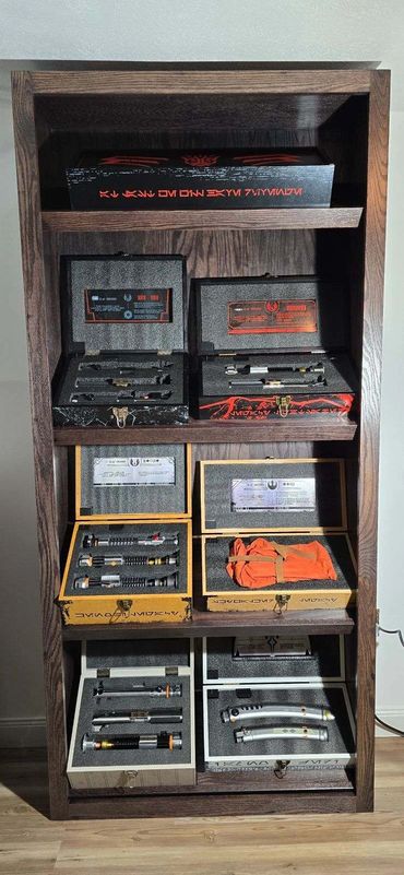 A wooden shelf displaying multiple open boxes with Star Wars lightsaber parts.