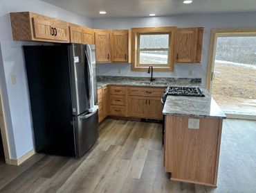 Modern kitchen with wooden cabinets and marble countertops.