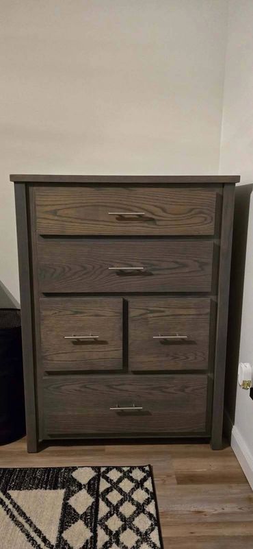 Dark wooden chest of drawers with metal handles.