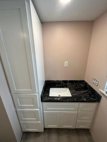 A white bathroom vanity with a black marble countertop and sink.