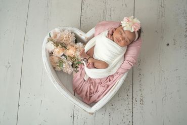 newborn/baby in a heartshaped box with flowers