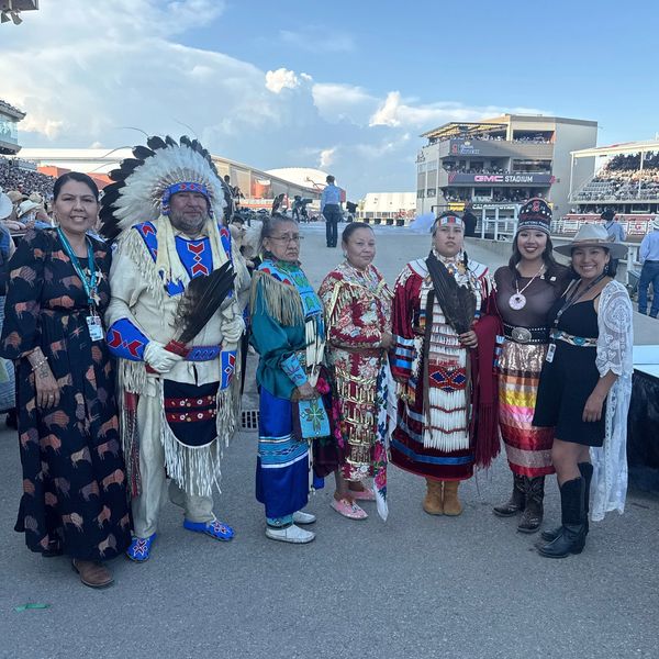 Group of people in Native American regalia at a stadium.