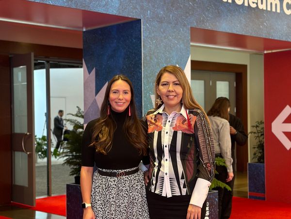 Two women posing and smiling indoors at an event.